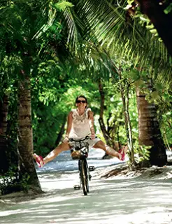 Woman cycling under palm trees