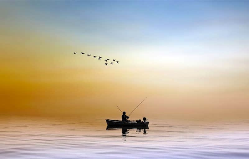 Fisherman in boat on calm water