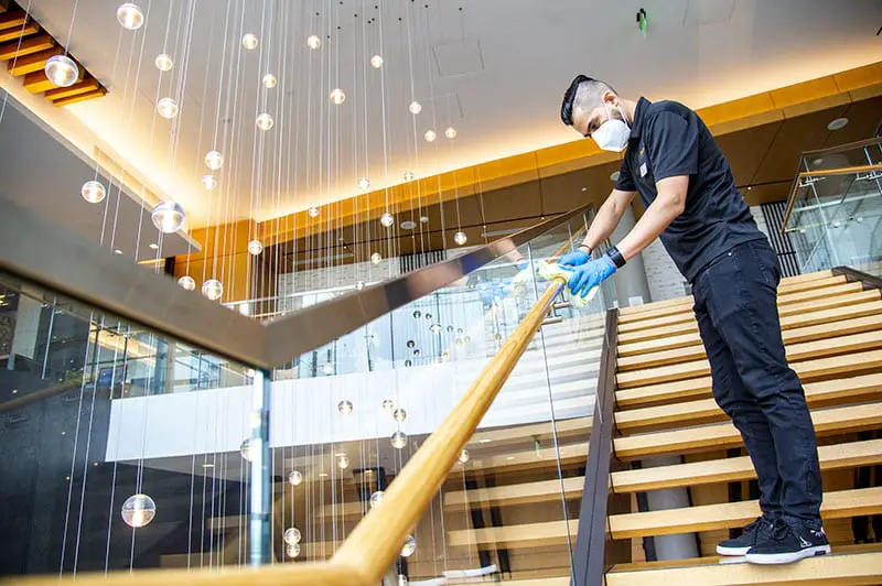 man disinfecting handrails at a hotel stairway
